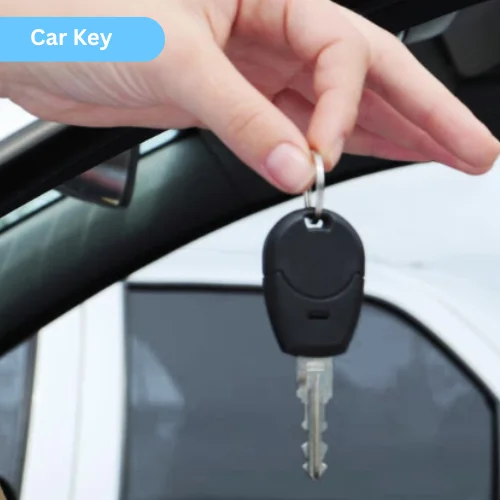 Photo of a hand holding a black car key with metal blade in front of a car interior.
