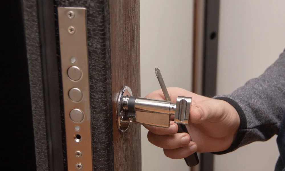 Close-up of a locksmith rekeying a residential door lock by removing the lock cylinder.
