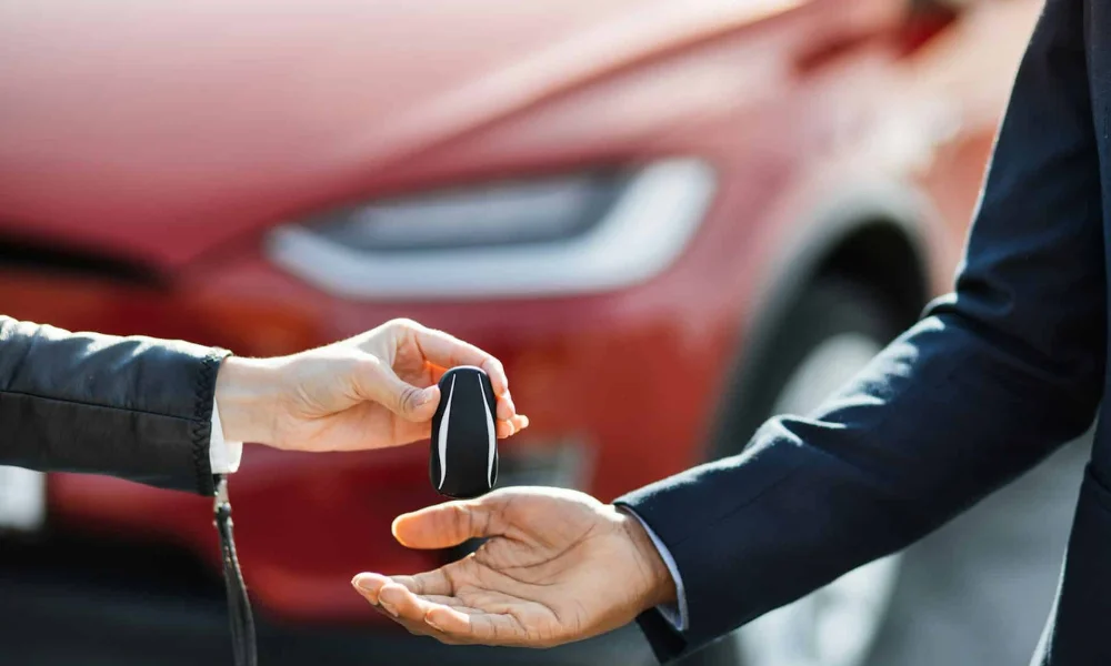Automotive locksmith handing over a car key fob during vehicle key replacement service