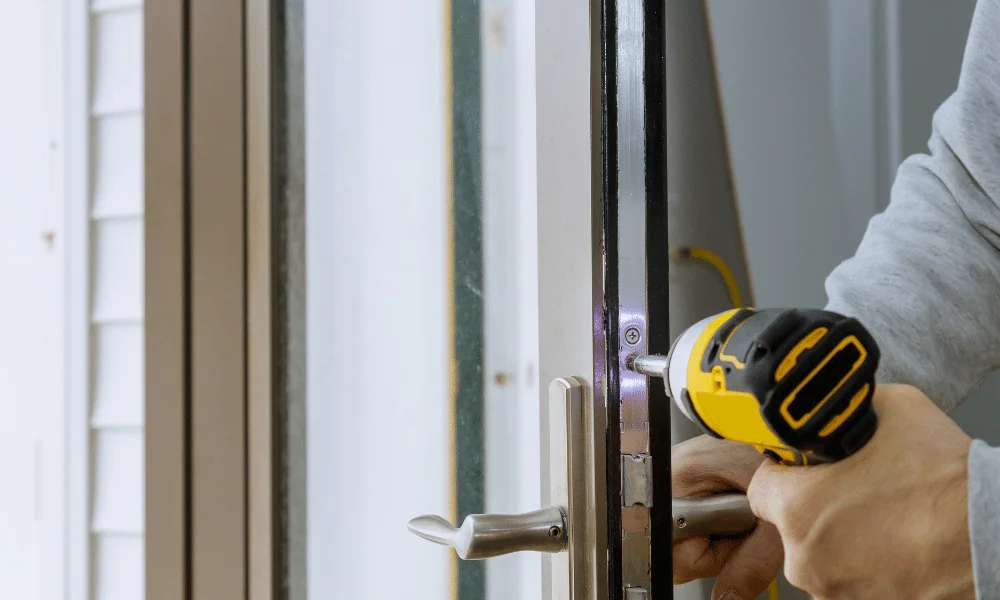 Residential locksmith installing or repairing a door lock using a power drill on a home entrance door