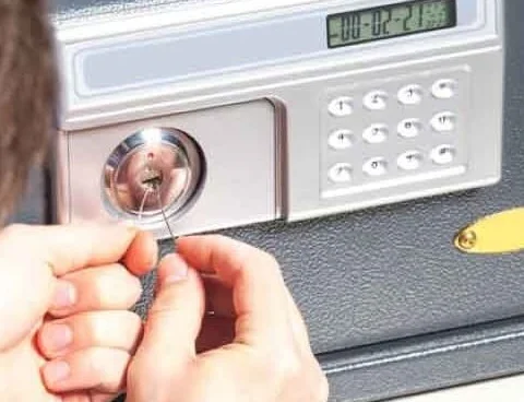 A locksmith opening a security vault box. The image shows the locksmith’s hands holding lock-picking tools to work on the vault’s lock. On the right side of the lock, there is a keypad, with a digital panel above it displaying the time. This image represents emergency locksmith service in Spring, Texas.