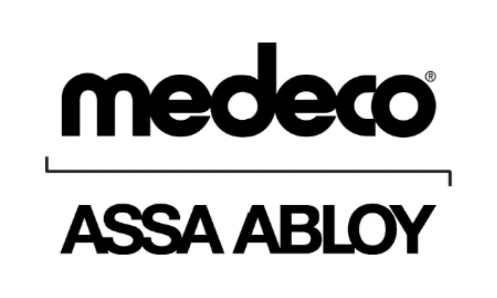 Medeco lock brand logo featuring the word “medeco” in bold black lowercase lettering with a distinctive stylized typeface and a registered trademark symbol near the upper-right. A thin black horizontal line separates the Medeco name from “ASSA ABLOY” in bold black uppercase lettering below, all displayed on a plain white background. The image represents the Medeco lock brand.